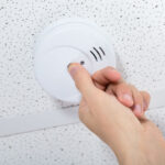 Man fixing fire alarm on a commercial ceiling.