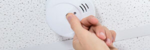 Man fixing fire alarm on a commercial ceiling.